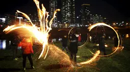 Sejumlah anak memutarkan kaleng berisi kayu yang dibakar jelang perayaan "Jeongwol Daeboreum"di sebuah taman di Seoul, Korea Selatan, Minggu (21/2). Tarian api ini merupakan bagian dari perayaan Imlek ala Korea. (REUTERS/Kim Hong-Ji)