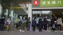 Orang-orang yang memakai masker berbaris di luar sebuah bank di Hong Kong, 8 Maret 2022. COVID-19 varian Omicron yang menyebar cepat membanjiri Hong Kong serta mendorong pengujian massal, karantina, pembelian panik di supermarket, dan rumah sakit kekurangan tempat tidur. (AP Photo/Kin Cheung)