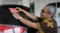 Kepala Dinas Pekerjaan Umum Bina Marga dan Cipta Karya Jateng, AR Hanung Triyono saat menempelkan stiker bertuliskan ‘Nek Aku Korupsi Ora Slamet’ di mobil dinasnya, Selasa (10/12/2019)