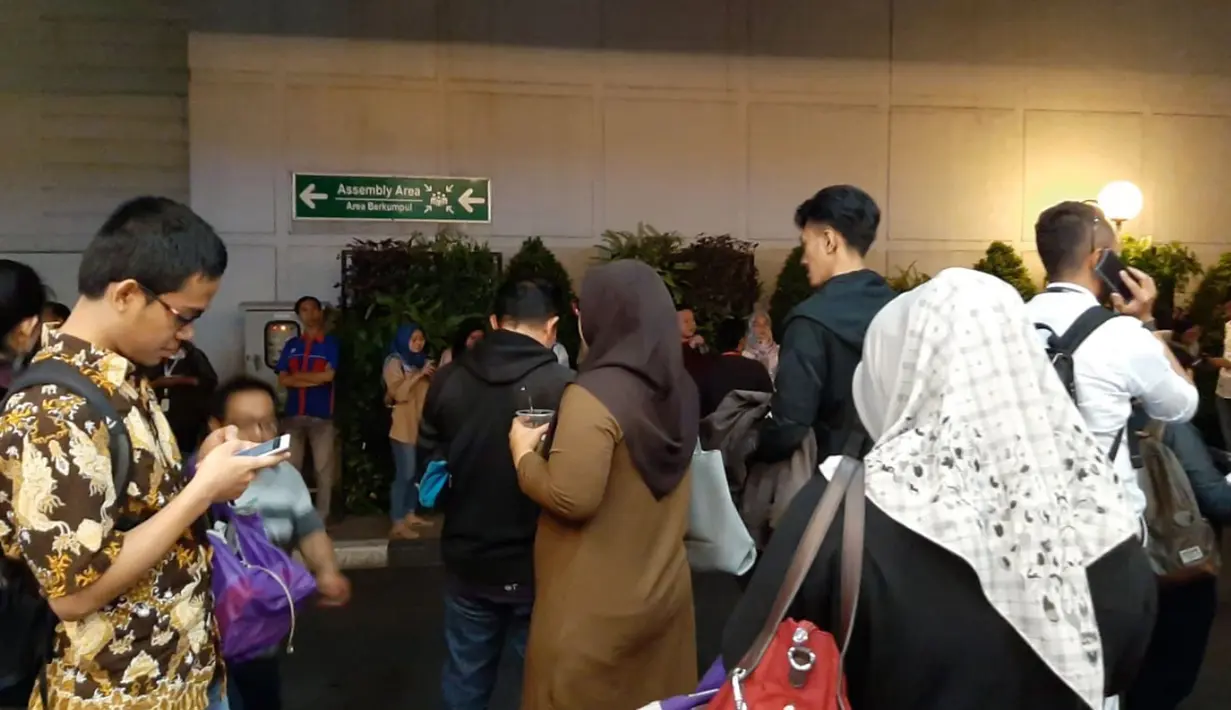 Sejumlah karyawan berkumpul di luar gedung perkantoran setelah merasakan gempa di Serpong, Tangerang pada Jumat (2/8/2019). Data dari BMKG, gempa dengan kekuatan magnitudo 7,4 mengguncang hingga Jakarta dan sekitarnya dengan pusat gempa berada di 147 km Barat Daya Sumur, Banten. (INDARYANI/AFP)