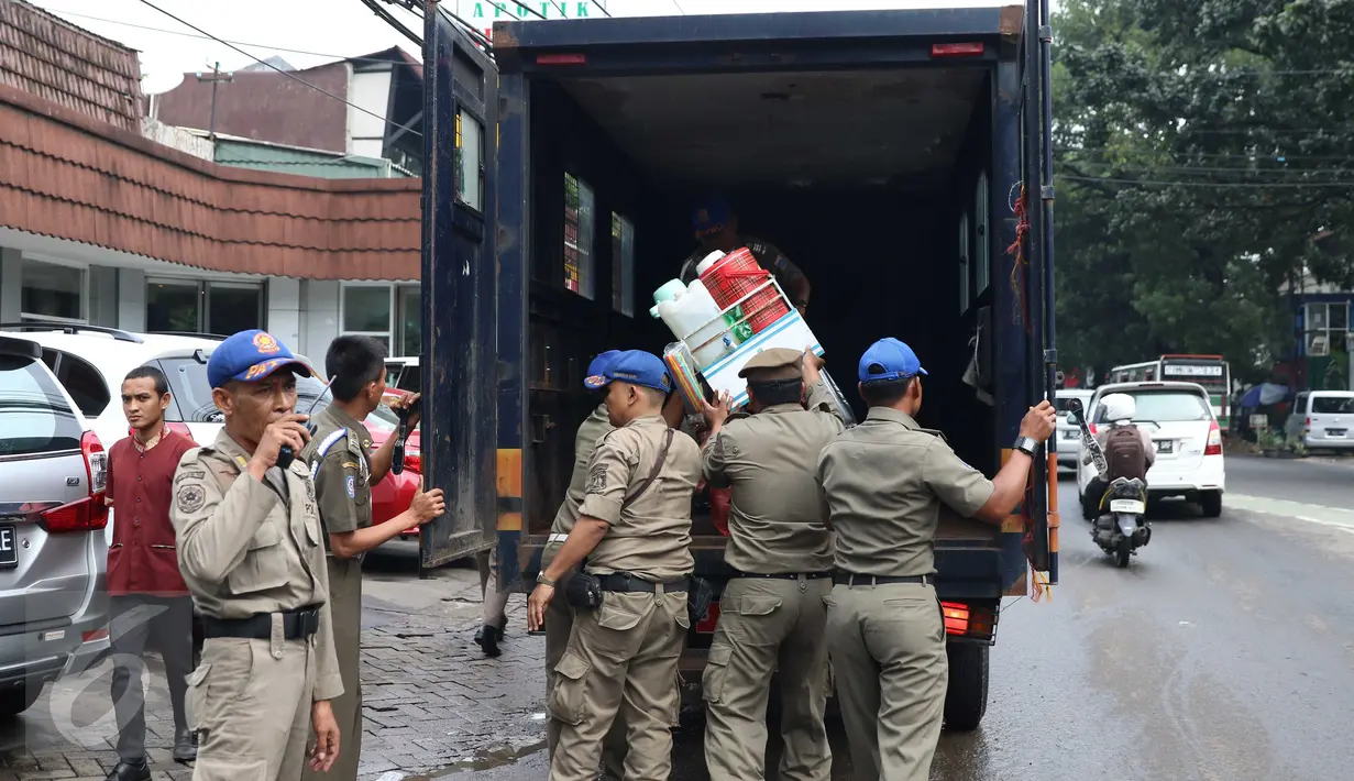 Petugas Satpol PP menaikkan barang dagangan milik pedagang kopi keliling ke atas mobil dalam penertiban di kawasan SCBD, Jakarta, Senin (21/11). Satpol PP merazia dan menyita dagangan yang beroperasi di kawasan tersebut. (Liputan6.com/Gempur M Surya)