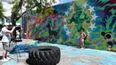 Pengunjung berpose di depan mural karya seniman Ron English di kawasan Wynwood, Miami, Florida pada 28 September 2016. Goldman Properties menggelar pameran mural untuk merevitalisasi lingkungan. (AFP PHOTO / Rhona WISE)