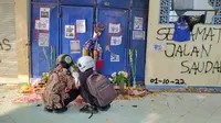 Dua orang pelajar menabur bunga dan berdoa di depan pintu 13 Stadion Kanjuruhan Malang. Mereka mendoakan para korban tragedi pada 1 Oktober 2022 dan berharap&nbsp;kelak kejadian serupa tak terulang lagi (Liputan6.com/Zainul Arifin)&nbsp;