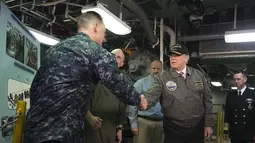 Presiden AS, Donald Trump berjaabat tangan dengan salah satu pasukan saat mengunjungi kapal induk Gerald R. Ford di Newport News, Virginia (2/3). Trump tampak gagah mengenakan jaket panglima tertinggi Navy Seal. (AFP Photo / Saul Loeb)