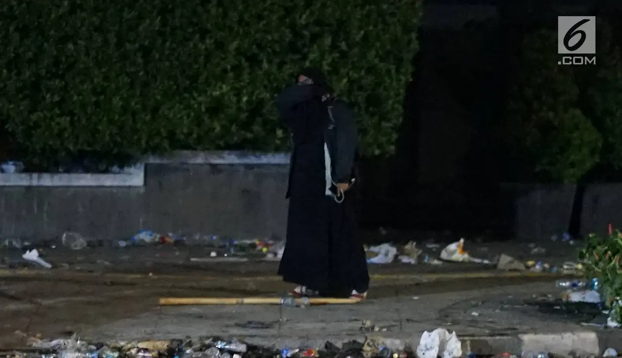Seorang perempuan bercadar hitam dengan kabel menjuntai di tangan berusaha mendekat Gedung Bawaslu, Jakarta, Rabu (22/5/2019). Perempuan misterius dengan baju gamis warna hitam berbalik badan dan menjauh dari gedung Bawaslu setelah polisi menembakkan gas air mata. (Liputan6.com/Immanuel Antonius)