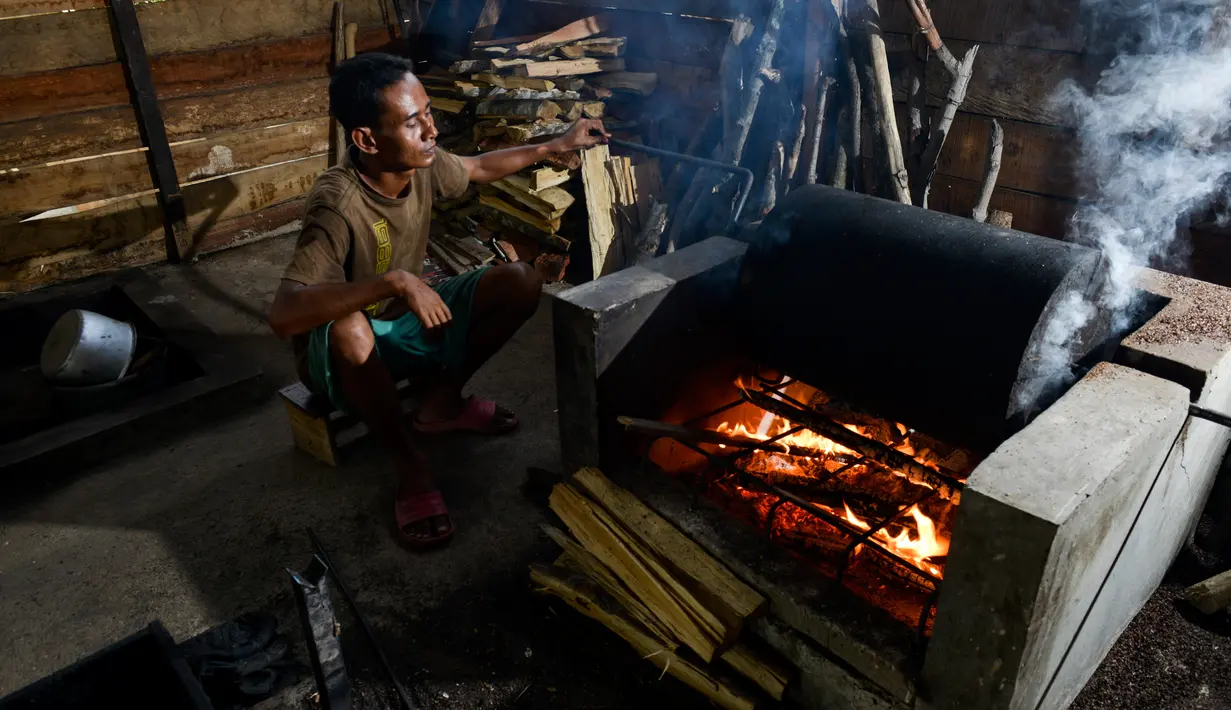 Seorang pria memanggang biji kopi robusta menggunakan alat tradisional di salah satu industri rumah tangga di Ulee Kareng, Aceh, Rabu (20/11/2019). Kopi yang diolah secara tradisional itu dijual dengan kisaran harga beragam tergantung kualitas. (CHAIDEER MAHYUDDIN/AFP)