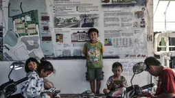 Anak-anak bermain di dekat poster desain Kampung Susun Akuarium, Penjaringan, Jakarta, Kamis (11/3/2021). Seperti diketahui, Kampung Susun Akuarium memiliki 5 blok masing-masing terdiri dari 5 lantai dengan jumlah total 241 unit. (merdeka.com/Iqbal S. Nugroho)