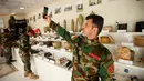 Seorang militer Kurdi Peshmerga berswafoto di sebelah bahan peledak dan barang-barang yang digunakan oleh militan Negara Islam (ISIS) di sebuah museum di Erbil, Irak, 12 Mei 2019. 'Museum ISIS' tersebut dibuka oleh militer Peshmerga. (REUTERS/Azad Lashkari)