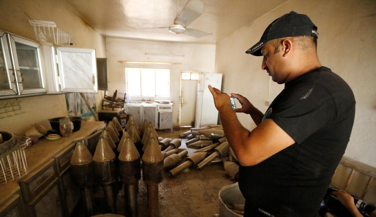 Anggota pasukan kontraterorisme Irak mengambil gambar senjata yang berada di bangunan yang digunakan sebagai pabrik senjata militan ISIS yang berhasil ditemukan di Fallujah, Irak, Kamis (23/6). (REUTERS/Thaier Al-Sudani)