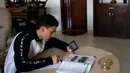 Siswa melihat telepon genggamnya saat mengikuti materi pelajaran yang disampaikan guru dari stasiun radio pendidikan di Jalur Gaza, Palestina, Minggu (15/3/2020). Metode ini digunakan untuk mencegah penyebaran virus corona COVID-19 di Jalur Gaza. (MOHAMMED ABED/AFP)