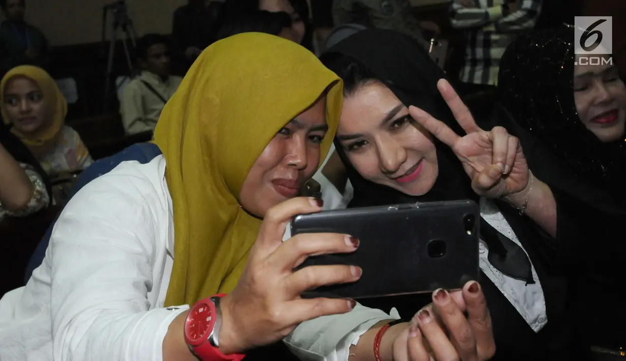 Bupati nonaktif Kutai Kartanegara, Rita Widyasari (kanan) berswafoto bersama kerabatnya jelang mengikuti sidang perdana di Pengadilan Tipikor, Jakarta, Rabu (21/2). Sidang mendengar dakwaan Jaksa Penuntut Umum. (Liputan6.com/Helmi Fithriansyah)