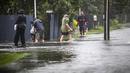 Orang-orang berjalan melewati banjir di Hastings, tenggara Auckland, Selandia Baru, Selasa (14/2/2023). Badai itu sampai mengakibatkan listrik di puluhan ribu rumah padam. Layanan kereta di Auckland juga dibatalkan. Perpustakaan hingga sekolah juga ditutup selama badai melanda negara itu. (Paul Taylor/Hawkes Bay Today via AP)