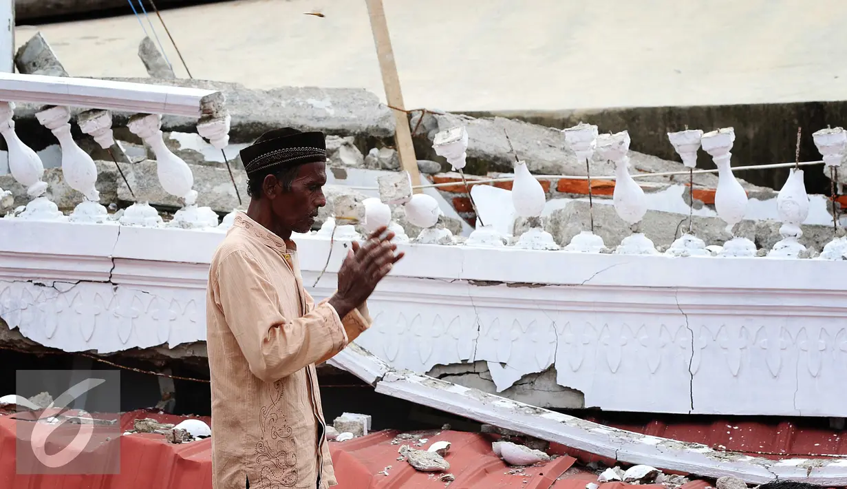 Seorang warga melaksanakan salat di halaman Masjid Jami Quba, Pidie Jaya, Aceh, Jumat (9/12). Gempa berkekuatan 6,5 SR telah merobohkan ratusan bangunan termasuk Masjid Jami Quba. (Liputan6.com/Angga Yuniar)