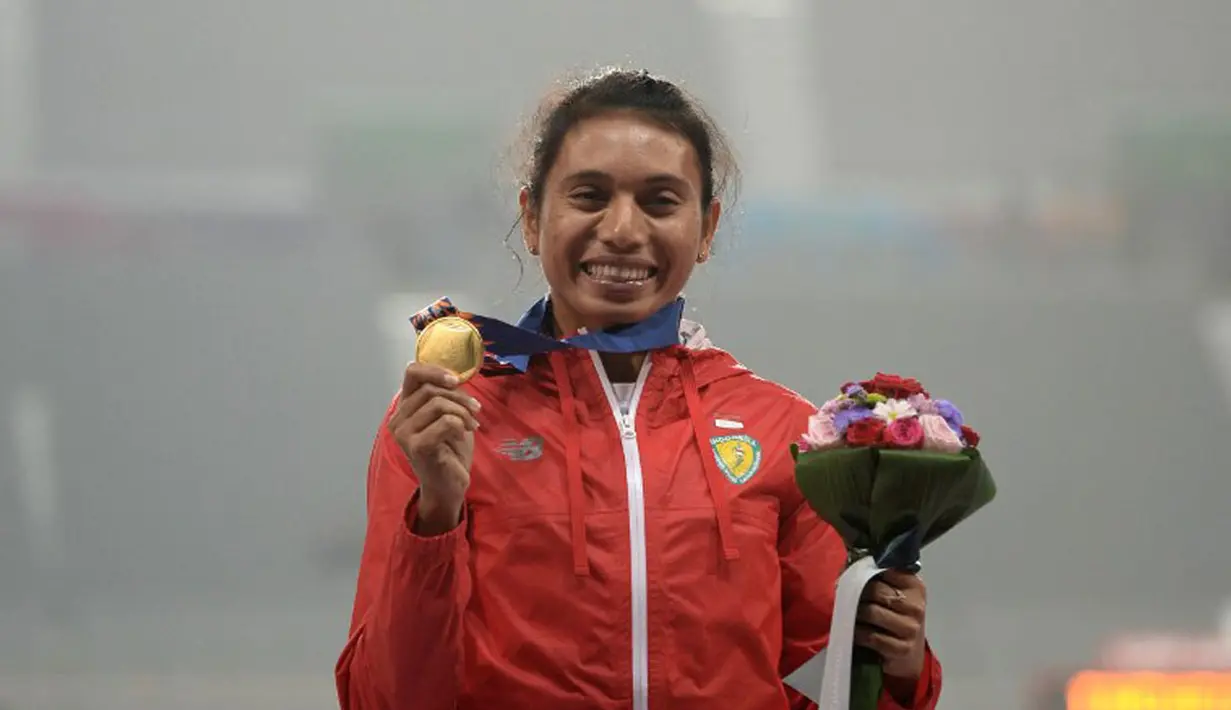 Atlet Lompat Jauh Indonesia, Maria Natalia Londa, berhasil menambah pundi emas tim Indonesia di Asian Games 2014. Maria Natalia Londa berpose dengan medalinya di podium kemenangan, (29/9/2014). (AFP PHOTO/Manan Vatsyayana)