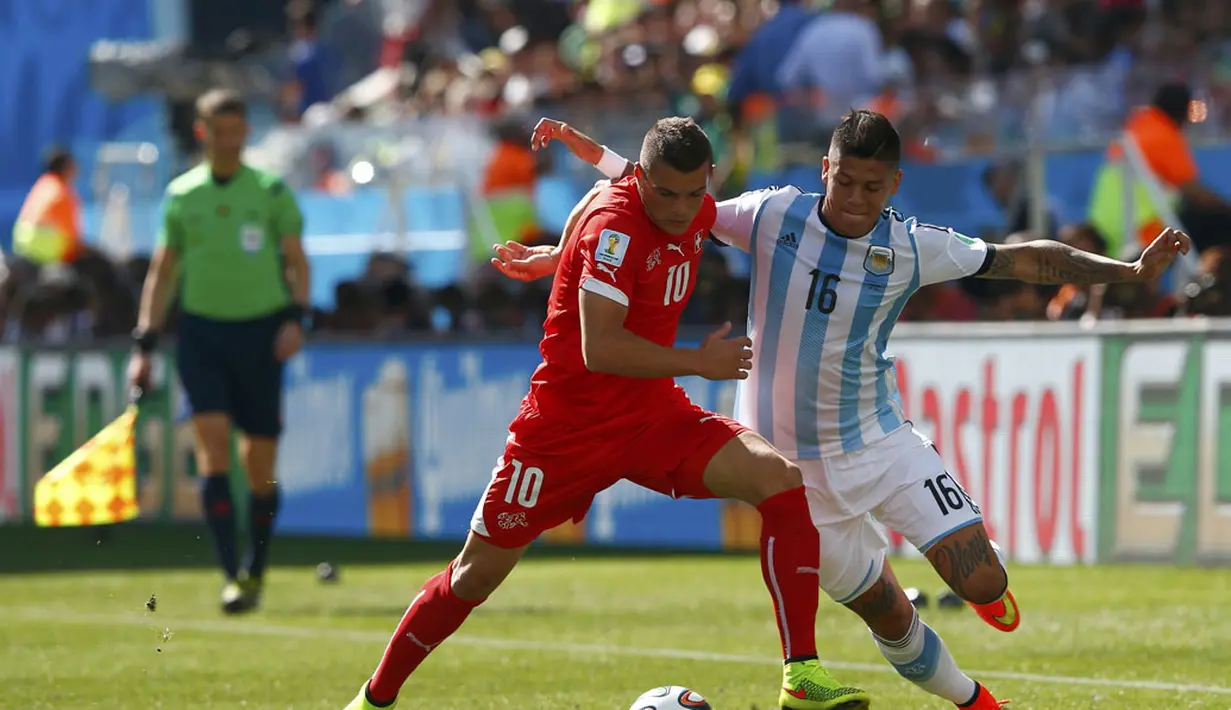 Pemain belakang Timnas Argentina, Marcos Rojo (kanan) mencoba melewati hadangan Granit Xhaka (Swiss) saat berlaga di 16 besar Piala Dunia 2014 di Stadion Corinthians, Sao Paulo, (1/7/2014). (REUTERS/Eddie Keogh)