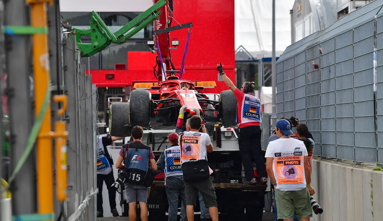 Mobil milik pebalap Ferrari, Sebastian Vettel diangkut truk pada balapan F1 Grand Prix di Hockenheim racing circuit, Jerman, (22/7/2018). Vettel kehilangan kendali saat perubahan cuaca dan menabrak pembatas. (AFP/ Andrej Isakovic)