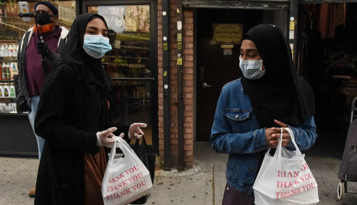 Dua wanita menerima makanan Halal gratis untuk Iftar selama bulan suci Ramadan di depan Masjid di masjid Taqwa, Brooklyn, New York (14/5/2020). Acara ini untuk menghormati ibu Wakil Advokat Publik Kashif Hussain meninggal karena COVID-19 pada 7 April 2020. (Stephanie Keith/Getty Images/AFP)