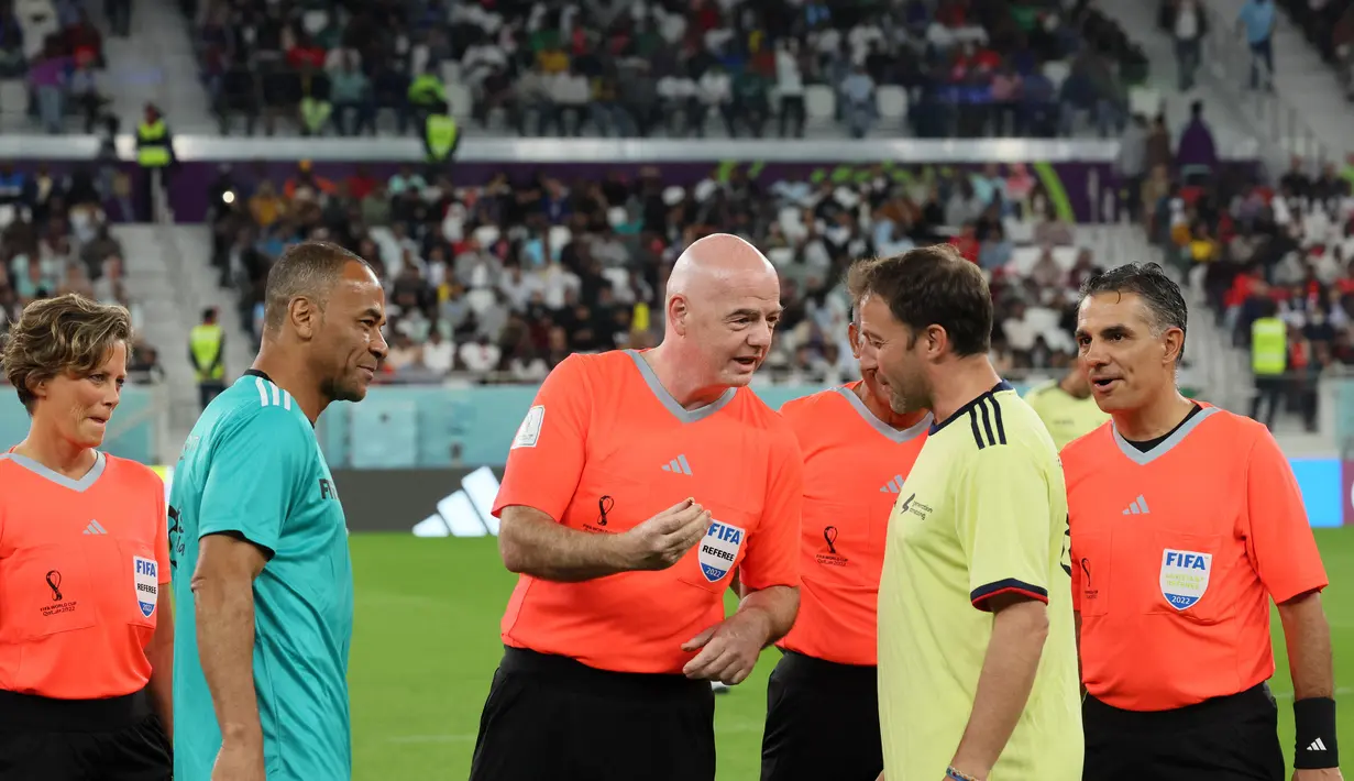 Presiden FIFA Gianni Infantino (tengah) mengenakan seragam wasit melempar koin di samping mantan pemain Brasil Cafu dan mantan pemain Italia Alessandro Del Piero saat ia memimpin pertandingan persahabatan antara FIFA Legends dan pekerja yang berbasis di Qatar di Al Stadion Thumama di Doha (12/12/2022). (AFP/Karim Jaafar)