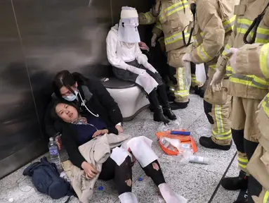 Seorang wanita korban kebakaran sedang menerima perawatan dari tim medis di Stasiun Tsim Sha Tsui, Hong Kong (10/2). Setelah polisi setempat menangkap seorang pria yang berusia 60 tahun, diduga kebakaran tersebut disengaja. (Handout / Apple Daily / AFP)