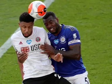Penyerang Sheffield United, Lys Mousset melompat saat berebut bola dengan bek Leicester City, Wes Morgan dalam lanjutan Liga Inggris pekan ke-36 di Stadion King Power, Kamis (16/7/2020). Leicester City sukses menggulung tamunya, Sheffield United dengan skor 2-0. (David Davies/Pool via AP)