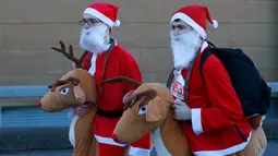 Dua orang pria yang mengenakan kostum Santa Claus lengkap dengan boneka rusa mengikuti balap lari Santa Dash di Liverpool, Inggris, Minggu (4/12). (Reuters/Phil Noble)