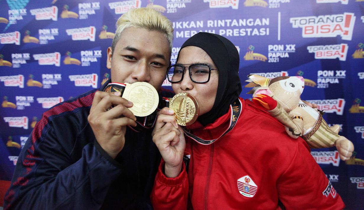 Pasangan suami istri pesilat sama-sama peraih Medali Emas di kelas D  Tanding Putra Putri  dari Jawa Barat Hanifan Yudani Kusumah dan Pipiet Kamelia dari DKI Jakarta berfoto bersama pada PON XX PAPUA  di GOR Toware (12/10) Jayapura. (FOTO: PB PON XX PAPUA/TATAN AGUS RUSTANDI)