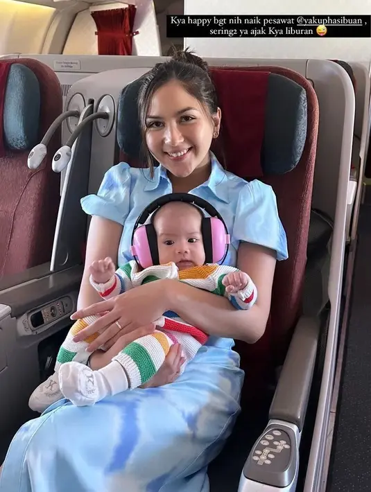 Gaya cantik Jessica Mila duduk di pesawat memangku sang buah hati. Ia tampil chic dengan dress berkerah lengan pendek berwarna biru muda. Kyarra juga tampil menggemaskan engan baju bayi bercorak garis berwarna-warni. [Foto: Instagram/jesicamila03]
