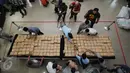 Petugas Dir IV Narkoba Mabes Polri membongkar dan merapikan puluhan pak ganja saat rilis di Jakarta, Selasa (24/5/2016). Petugas menahan enam orang tersangka dengan barang bukti narkoba jenis ganja seberat satu ton. (Liputan6.com/Helmi Fithriansyah)