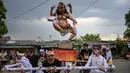 Bhuta Kala merepresentasikan kekuatan alam semesta dan waktu yang tak terhingga, yang divisualisasikan dalam bentuk raksasa atau makhluk menyeramkan sebagai simbol energi negatif atau kejahatan. Tampak dalam foto, para penganut Hindu membawa Ogoh-ogoh, patung yang melambangkan roh jahat, selama pawai menjelang Nyepi di Surabaya pada Rabu 18 Maret 2026. (JUNI KRISWANTO/AFP)
