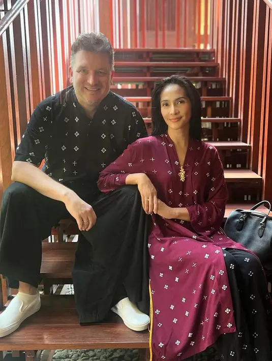 Maudy Koesnaedi  mengenakan pakaian corak batik yang serasi dengan suami. Maudy memilih mengenakan kebaya panjang modern warna maroon dipadukan bawahan hitam. [@maudykoesnaedi]