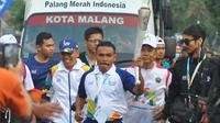 Petinju legendaris Indonesia, Nico Thomas, membawa obor Asian Games XVIII saat melintasi di Kota Malang, Jawa Timur, Jumat (20/7/2018). Sebanyak 10 kota di Indonesia akan dilalui oleh obor Asian Games. (Bola.com/Iwan Setiawan)