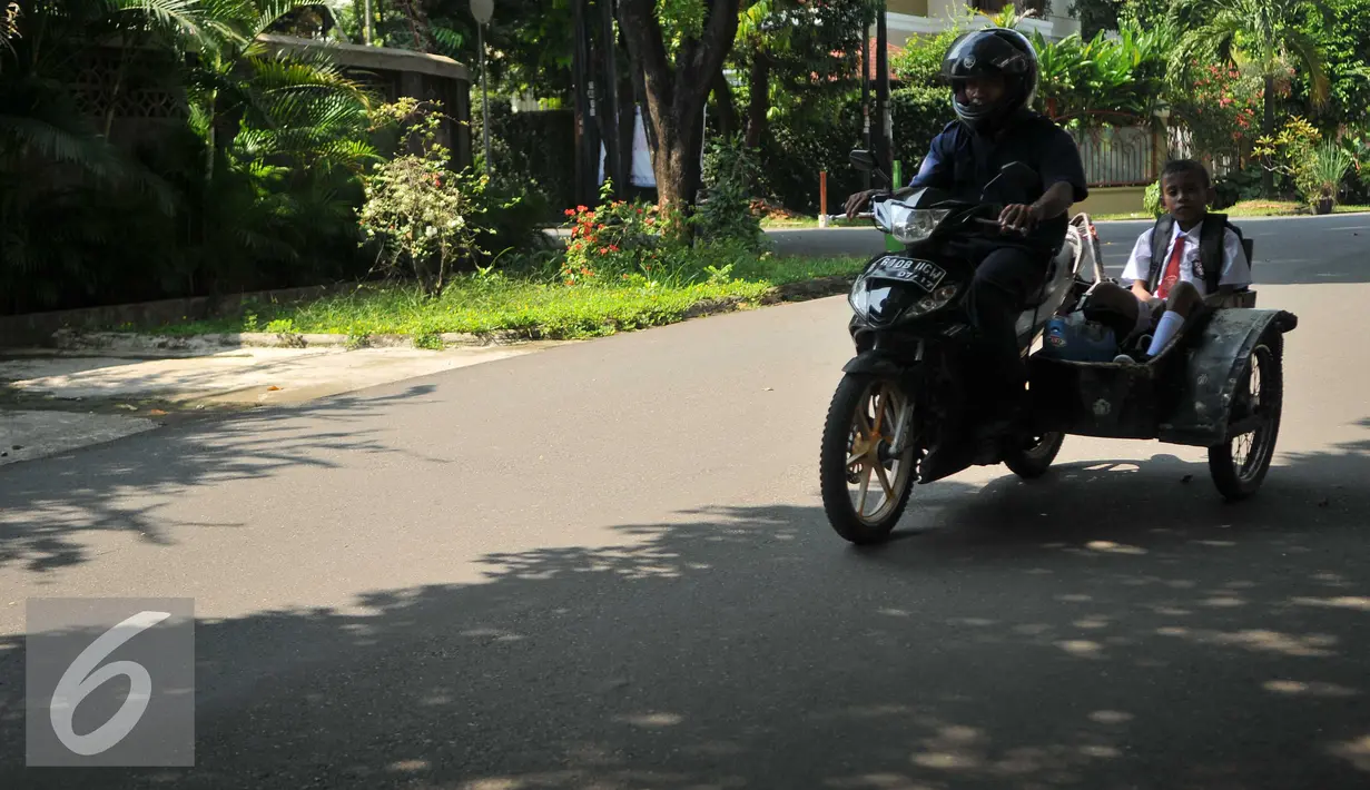 Orang tua mengunakana sepeda motor mengantar anaknya di hari pertama sekolah di SD Gunung 01, Jakarta, Senin (18/7). Usai libur panjang para siswa kembali bersekolah untuk tahun ajaran 2016-2017.(Liputan6.com/Gempur M Surya)
