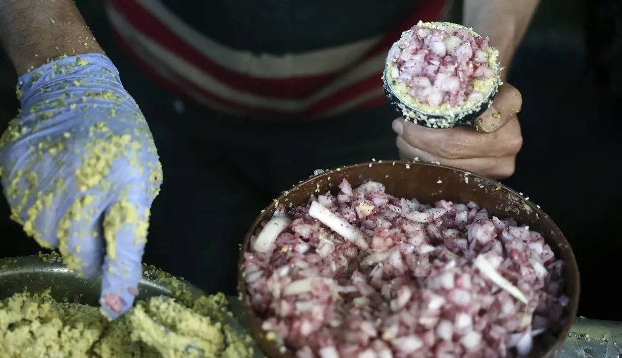 Seorang warga Palestina membuat falafel isi bawang bombay, makanan yang disantap saat berbuka puasa, selama bulan suci Ramadhan di pusat kota Hebron di Tepi Barat yang diduduki (9/4/2022). Falafel adalah sebuah makanan Timur Tengah. (AFP/Hazem Bader)
