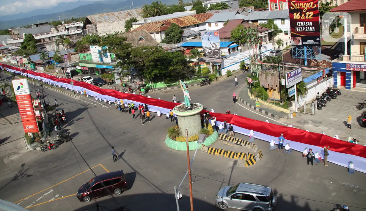 Pelajar SMA membentangkan bendera Merah Putih sepanjang 2,3 kilometer di Jalan Panjaitan dan Jalan Nani Wartabone, Gorontalo, Kamis (23/1/2020). Bendera dibentangan di tempat deklarasi kemerdekaan Gorontalo pada 23 Januari 1942. (Liputan6.com/Arfandi Ibrahim)
