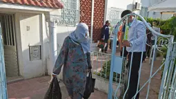 Warga membawa makanan berbuka puasa gratis dari relawan selama bulan suci Ramadan di Ariana, Tunisia (7/5/2020). Masjid-masjid di Aljazair, Maroko dan Tunisia telah ditutup untuk membatasi penyebaran Covid-19, mencegah doa malam khusus. (AFP/Fethi Belad)