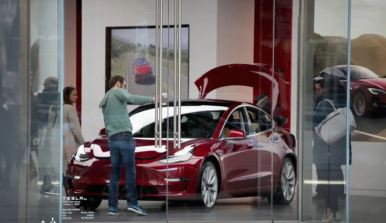 Pengunjung melihat mobil Tesla model 3 di sebuah dealer di Chicago, Illinois (30/3). Produsen mobil listrik Tesla mengkonfirmasi keterlibatan sistem autopilot kendaraannya dalam kecelakaan fatal pada 23 Maret 2018 lalu. (Scott Olson / Getty Images / AFP)