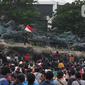 Massa aksi demo tolak omnibus law UU Cipta Kerja naik ke atas patung arjuna wiwaha mengibarkan bendera merah putih di Jalan Medan Merdeka Barat, Jakarta Pusat, Selasa (20/10/2020). Mereka sempat mengibarkan bendera selama kurang lebih lima menit di atas patung. (Liputan6.com/Herman Zakharia)