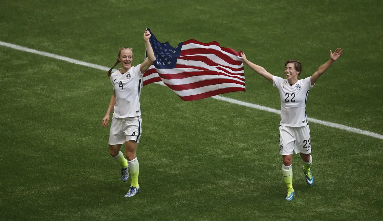 Bek AS, Becky Sauerbrunn (kiri) dan bek Meghan Klingenberg mengibarkan bendera merayakan gelar juara Piala Dunia wanita 2015 di BC Place, Kanada, Senin (6/7/2015). Amerika berhasil mengalahkan Jepang dengan skor 5-2.  (Reuters/Anne Marie Sorvin)