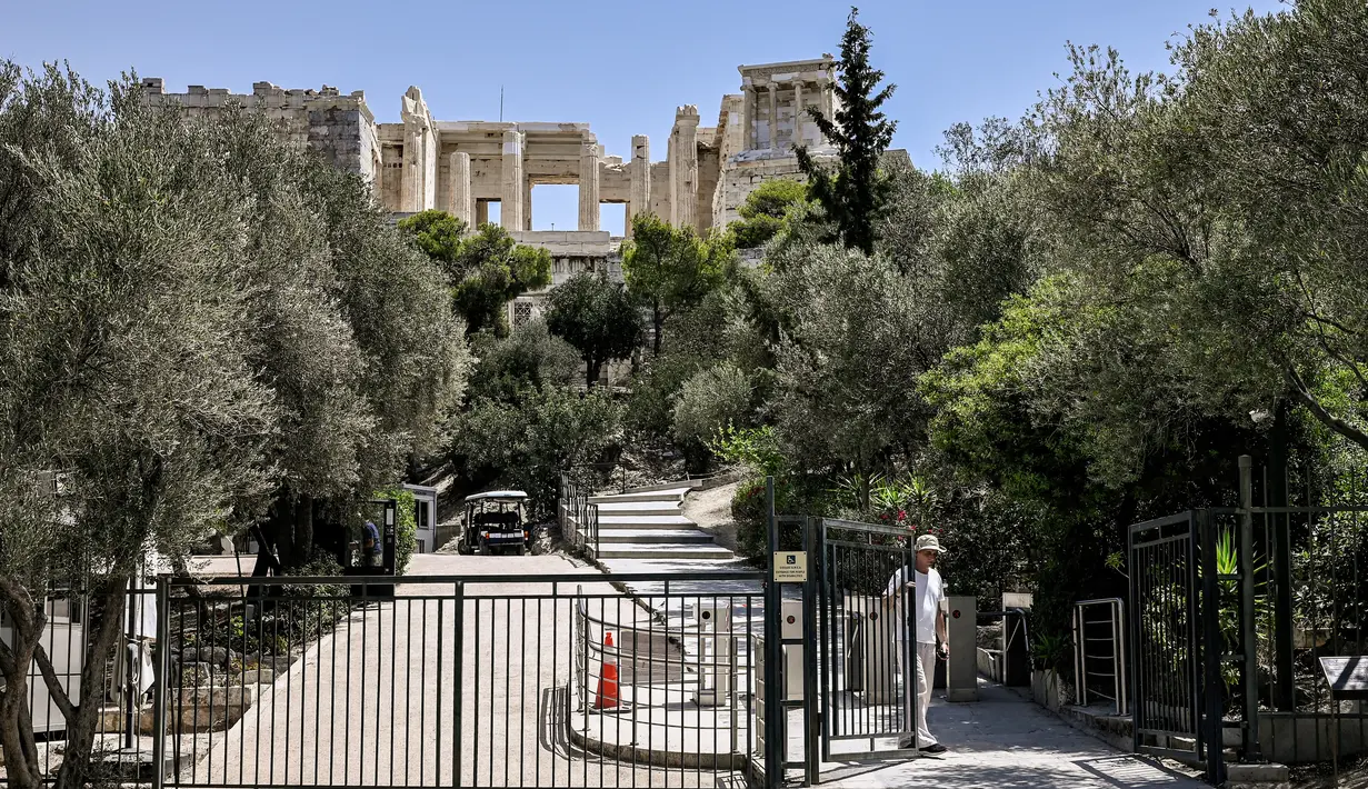 Seorang karyawan menutup gerbang akses ke situs arkeologi Acropolis di Athena pada 14 Juli 2023. (AFP/Spyros Bakalis)