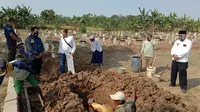 Polisi menguburkan jenazah pemulung yang tewas dipukul balok di Desa Wanajaya, Kabupaten Bekasi. (Liputan6.com/Bam Sinulingga)