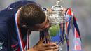 Pemain PSG, Kylian Mbappe mencium trofi Coupe De France 2023/2024 saat upacara penyerahan di Stade Pierre-Mauroy, Villeneuve-d'Ascq, Prancis, Minggu (26/05/2024) WIB. PSG menang dengan skor 2-1 atas Olympique Lyon pada babak final. (AFP/Denis Charlet)