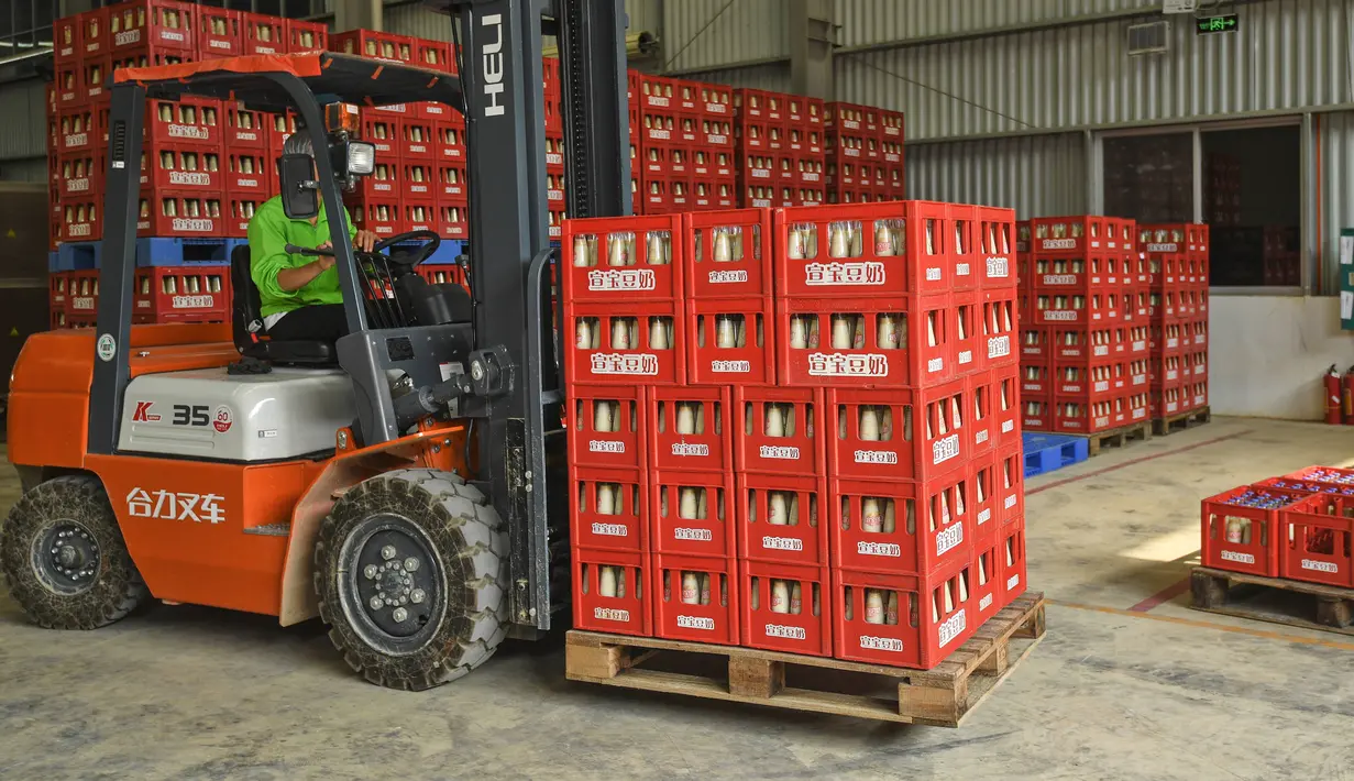 Pekerja memindahkan botol-botol susu kedelai di sebuah pabrik di Nanning, Guangxi, China, Selasa (12/3). Tekanan terhadap pabrikan asal China juga diperparah dengan menurunnya permintaan global. (STR/AFP)