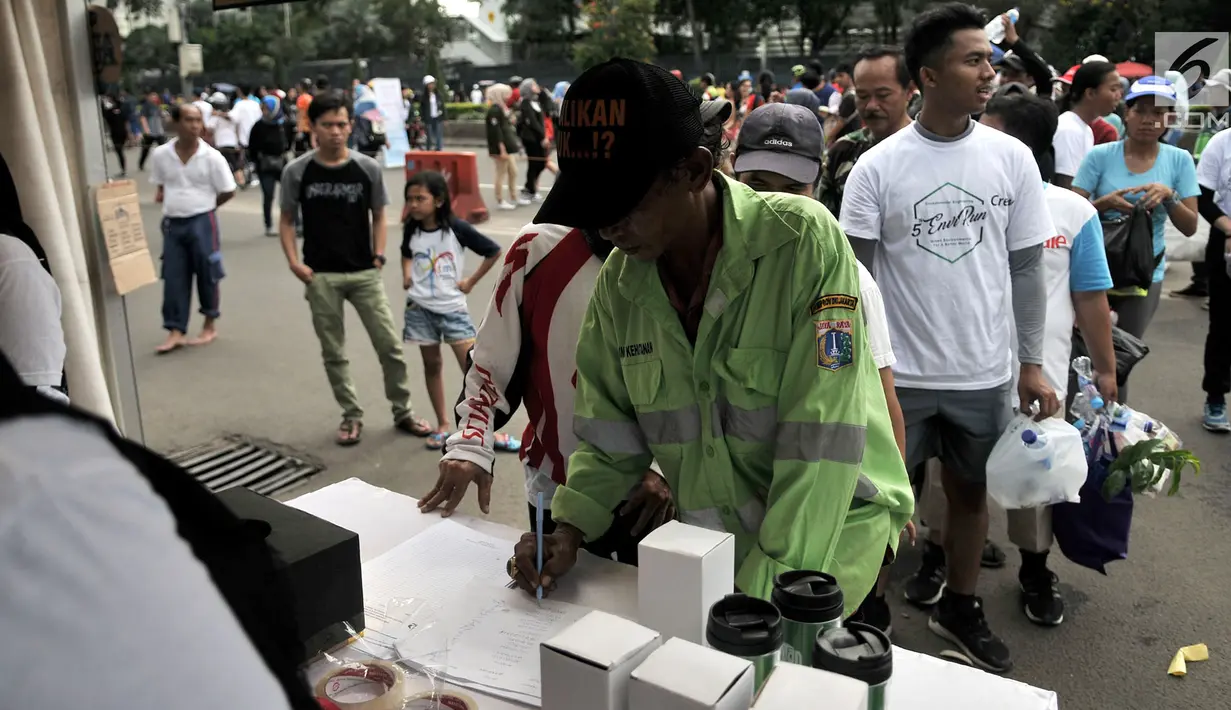 Warga mengisi data saat menukarkan botol bekas di stan ENVIRUN selama hari bebas kendaraan atau car free day (CFD) di Jakarta, Minggu (8/4). Kegiatan ini untuk mengurangi sampah botol plastik yang semakin mencemari lingkungan. (Merdeka.com/Iqbal Nugroho)