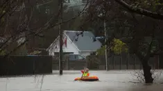 Warga menggunakan perahu kecil melintasi banjir di Christchurch, Selandia Baru, Sabtu, (22/7). Dewan Kota Christchurch mengatakan keadaan darurat setelah Sungai Heathcote meluap akibat cuaca yan buruk. (AP Photo / Mark Baker)
