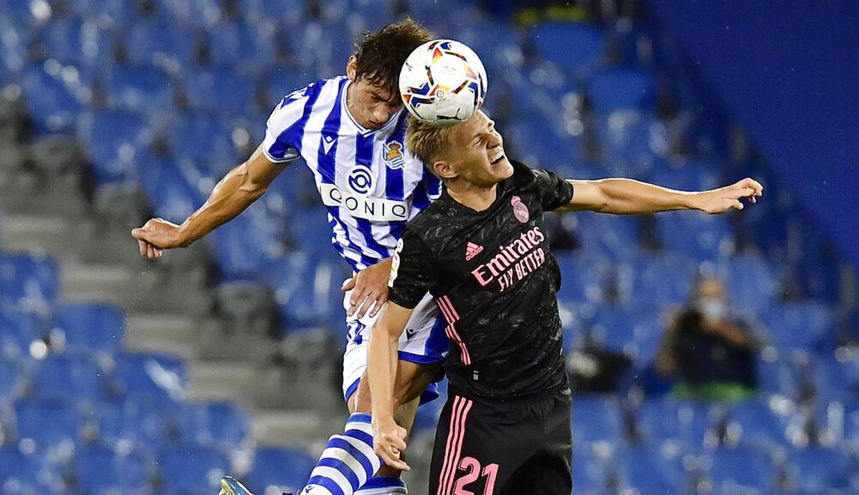 Pemain Real Madrid, Martin Odegaard, duel udara dengan pemain Real Sociedad, Robin Le Normand, pada laga Liga Spanyol di Stadion Anoeta, Minggu (20/9/2020). Kedua tim bermain imbang 0-0. (AP/Alvaro Barrientos)