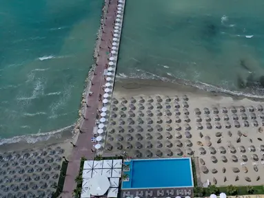 Foto udara pada 1 Juni 2020 menunjukkan payung-payung jerami di sebuah pantai di Qerret, dekat kota Kavaja, Albania. Rencananya pada 6 Juni mendatang, semua pantai umum akan dibuka untuk wisatawan setelah Albania menerapkan langkah-langkah pelonggaran pencegahan virus corona. (SHKULLAKU / AFP)