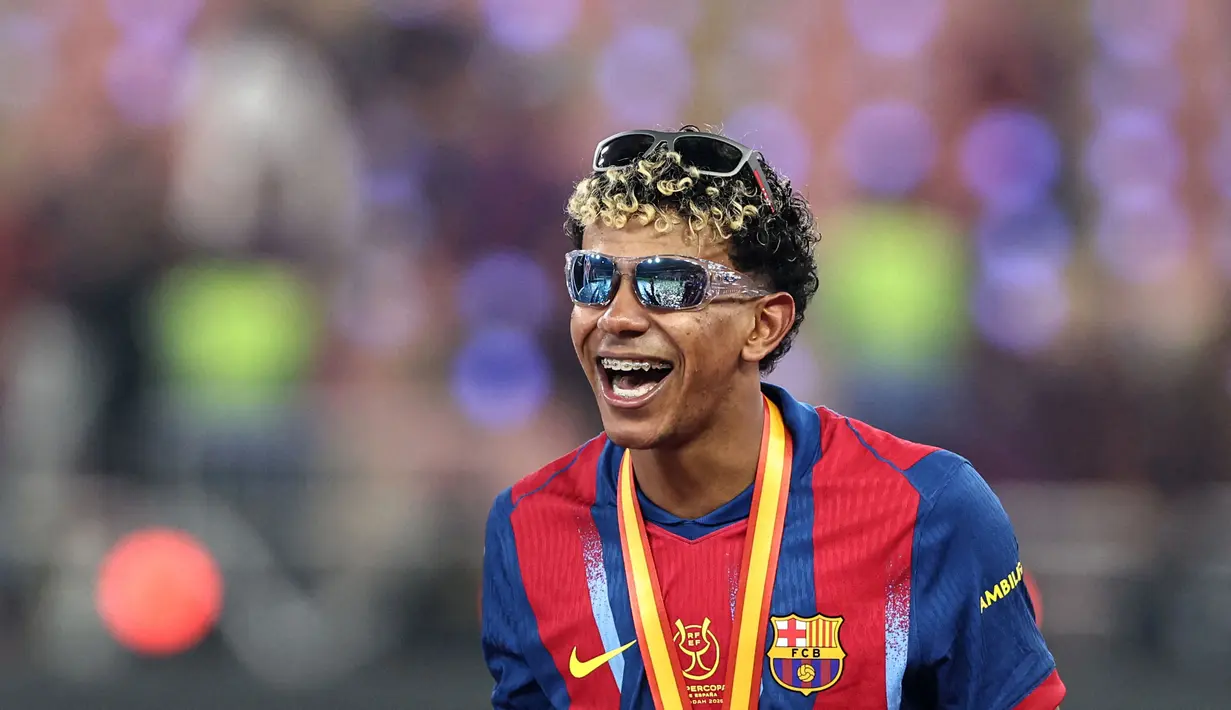 Pemain Barcelona, Lamine Yamal mengenakan dua kacamata saat merayakan gelar juara Piala Super Spanyol 2026 setelah mengalahkan Real Madrid dengan skor 3-2 dalam laga final yang berlangsung di King Abdullah Stadium, Jeddah, Arab Saudi, Minggu (11/01/2026) waktu setempat. (AFP/Fadel Senna)