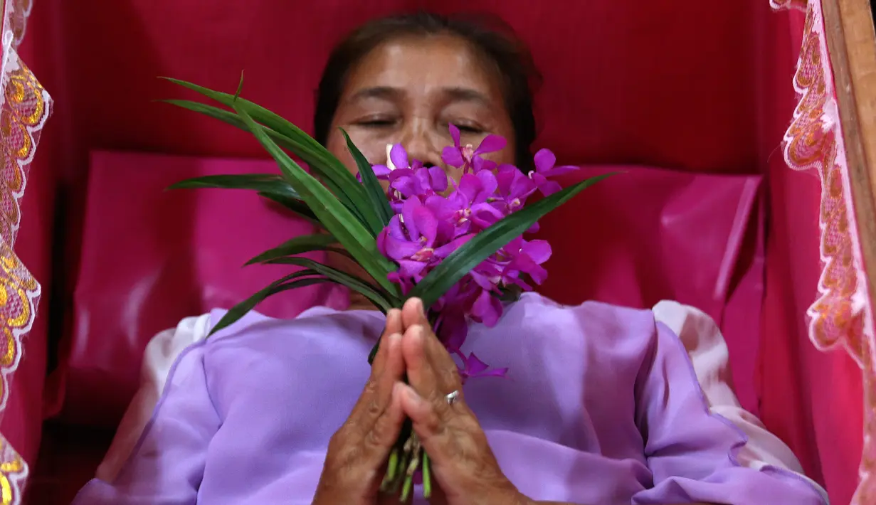 Seorang pemuja berdoa saat berbaring dalam peti mati di kuil Takien, pinggiran kota Bangkok, Thailand, Senin (31/12). Mereka mempercayai ritual ini dapat membantu menyingkirkan nasib buruk dan dianggap sebagai awal dari kehidupan baru. (AP/Sakchai lalit)
