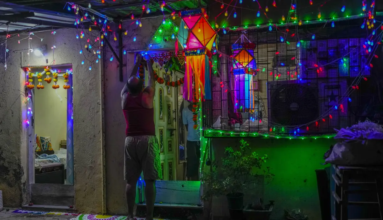 Seorang pria mendekorasi rumahnya selama Diwali, festival cahaya di Mumbai, India, Senin (24/10/2022). Warga India di seluruh negeri merayakan Diwali, festival Hindu yang melambangkan kemenangan cahaya atas kegelapan. (AP Photo/Rafiq Maqbool)