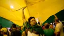 Demonstran membentangkan bendera Brasil saat menggelar aksi protes di Rio de Janeiro, Brasil (3/4). Sebelumnya, mantan Presiden Brasil Luiz Inacio Lula da Silva terbukti melakukan korupsi, dan menerima suap. (AP / Silvia Izquierdo)